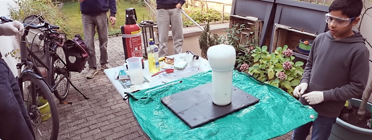 Die verblüffenden Effekte der Chemie führen schnell zu hilfreichen Rechnungen der Mathematik. Mehrere Zuschauer und Akteure rund um den Tischversuch zur Elefantenzahnpasta